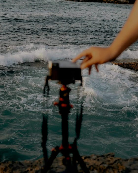 Camera on a tripod filming a surfer in the waves for video analysis